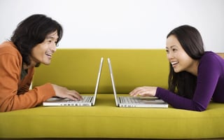 Photo of happy couple browsing for deals on their laptops